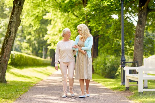 daughter with senior mother walking at summer park